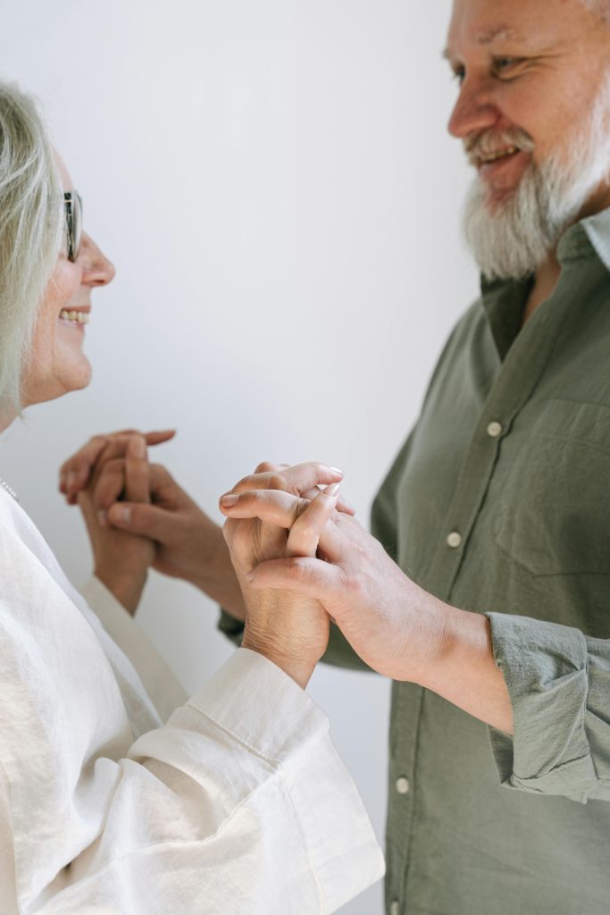 Elderly caucasian couple joyfully holding hands, symbolizing love and connection.