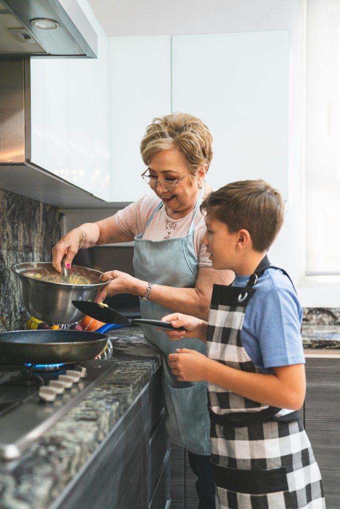 A joyful cooking scene with a grandmother and grandson preparing a meal together.